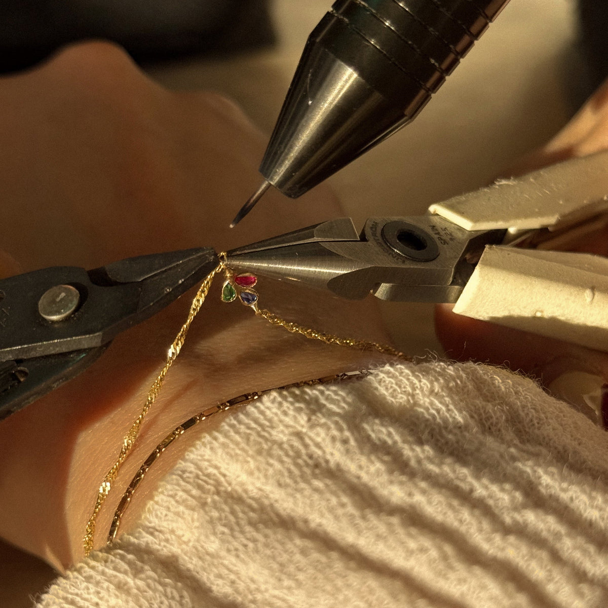 A close up of a gold chain bracelet being welded into place on a wrist.