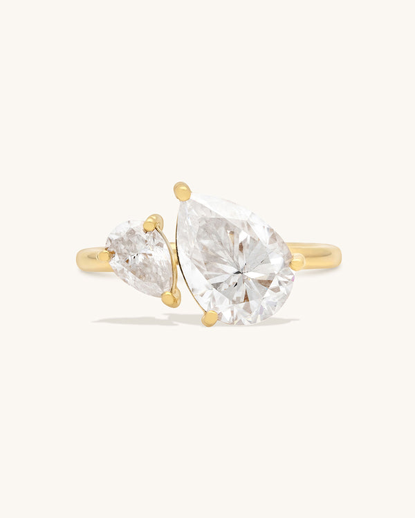 A gold ring with two pear shaped moissanite gems